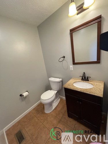 A bathroom with a toilet, sink, and mirror.