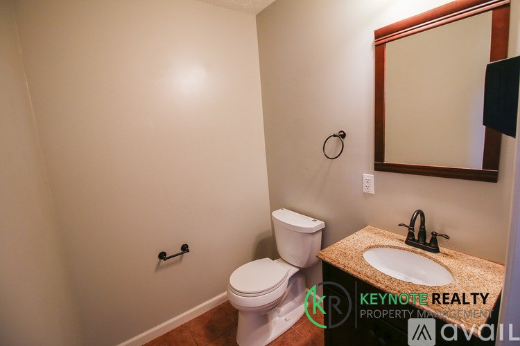 A bathroom with a toilet, sink and mirror.