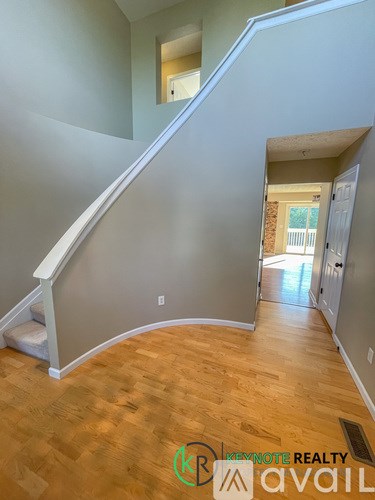 A hallway with wooden floors and a staircase leading to another room.