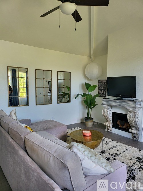 A living room with a grey couch, a fireplace, and a television.