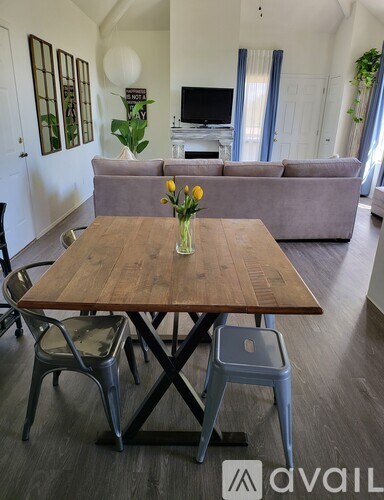 A wooden table with a vase of flowers on it and two chairs in front of it.