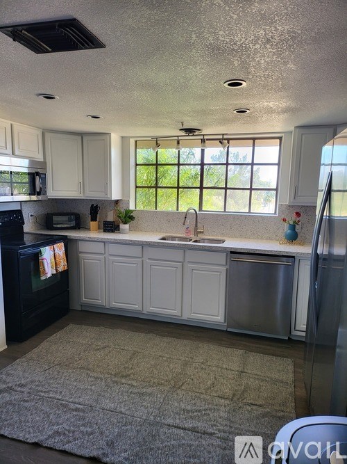 A kitchen with white cabinets and a large window.