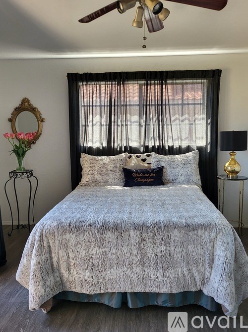 A bed with a grey comforter and pillow is in the center of the image.