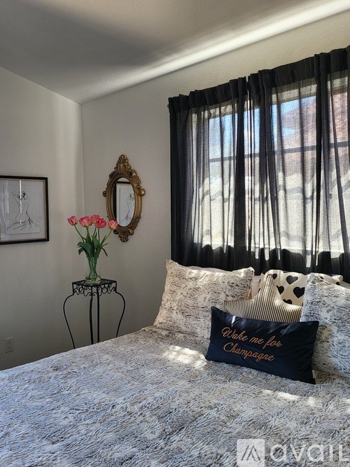 A bedroom with a bed, a mirror, a vase with flowers, and a pillow with the text "While me for Changagne".
