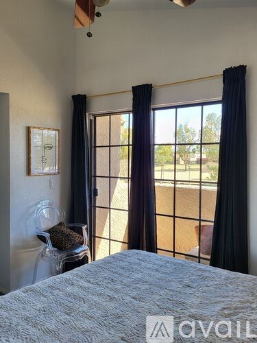 A bedroom with a bed, a window with curtains, and a picture on the wall.