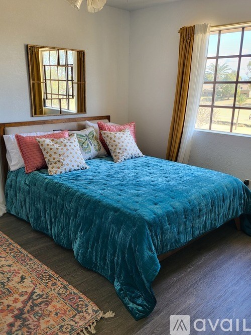 A bed with a blue velvet cover and a rug on the floor.