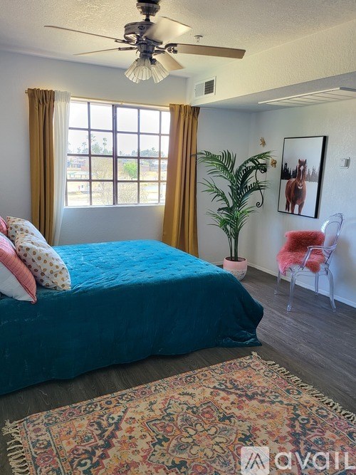 A bedroom with a blue bedspread and a ceiling fan.