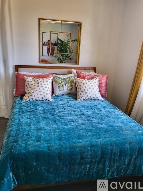A bed with a blue cover and four pillows.