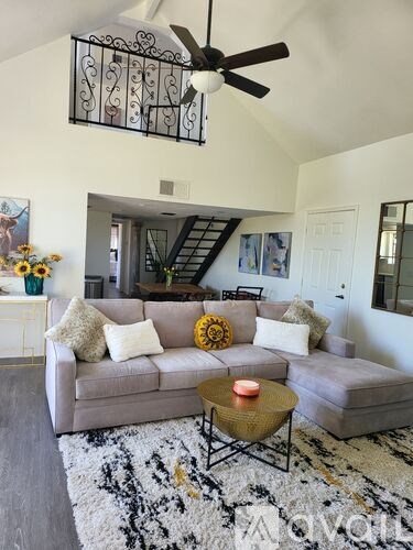 A living room with a grey couch and a black and white rug.