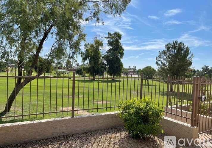 A metal fence with a green bush in front of it.