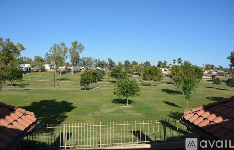 A view of a green lawn from a balcony with a fence in the foreground.