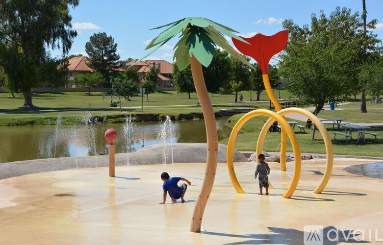 Two children playing in a water park with a palm tree sculpture.