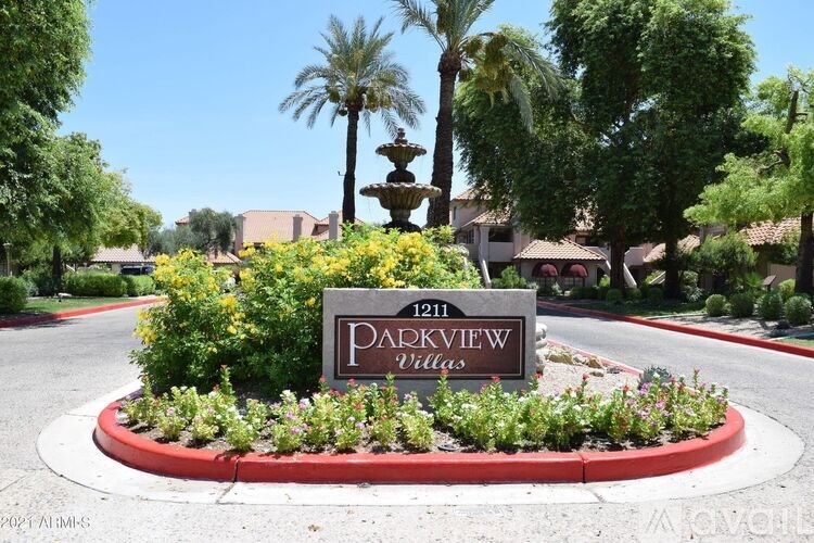 A sign for Parkview Villas is surrounded by flowers and greenery.