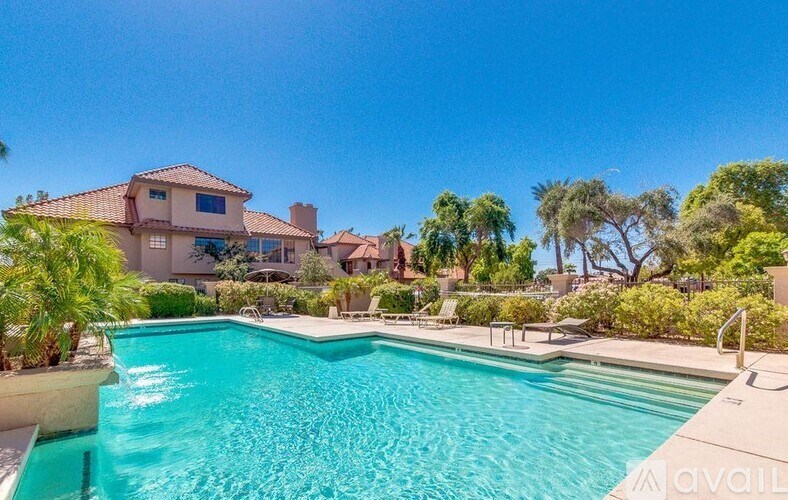 A swimming pool in front of a house with a clear blue sky.