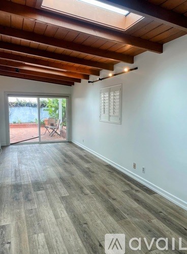 A room with wooden floors and a slanted ceiling with skylights.