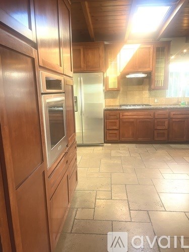 A kitchen with wooden cabinets and a tile floor.