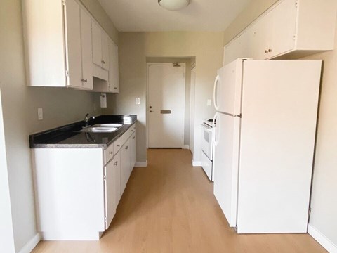 A kitchen with white cabinets and a white refrigerator.