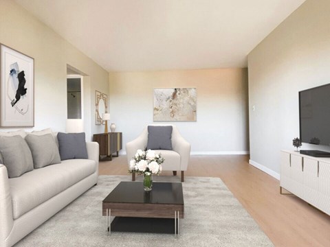 A living room with a white couch, a coffee table, and a television.