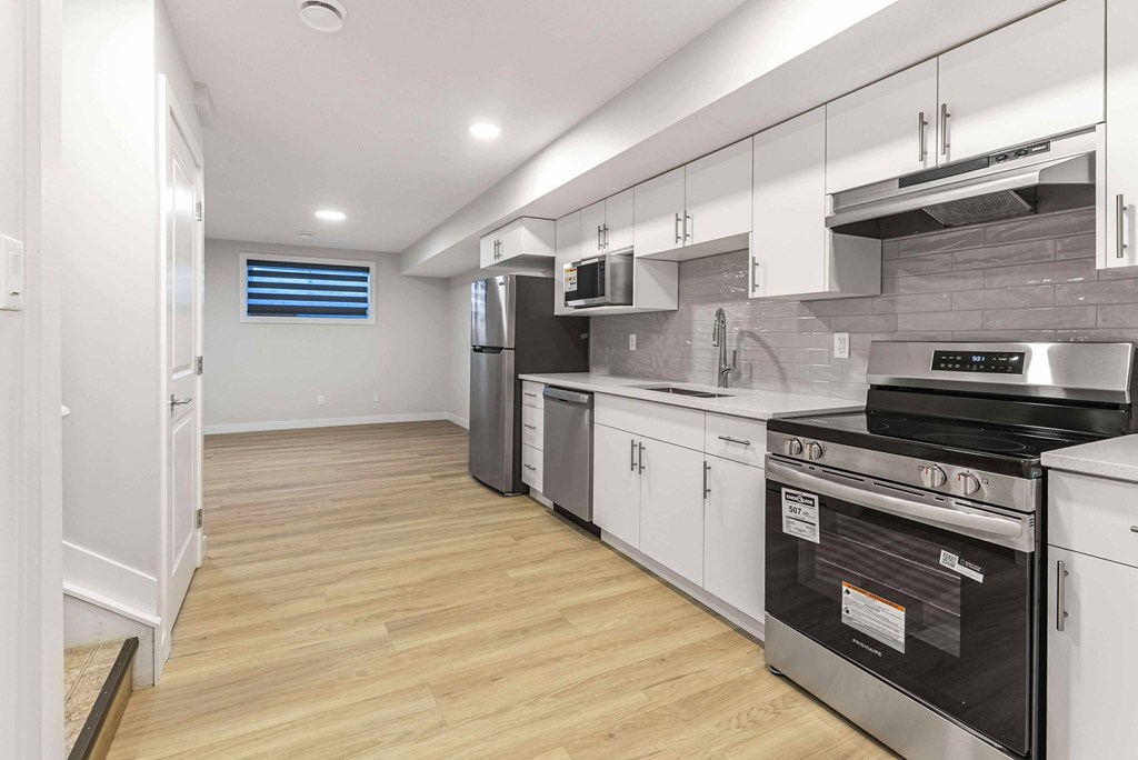 A kitchen with white cabinets and a wooden floor.