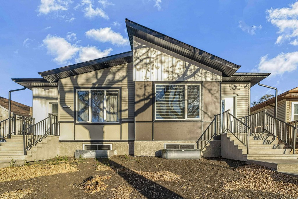 A modern house with a triangular roof and a front yard.