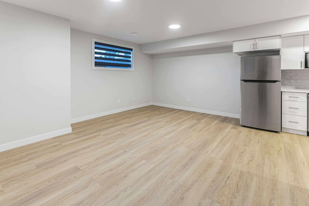 A kitchen with a wooden floor and a stainless steel refrigerator.