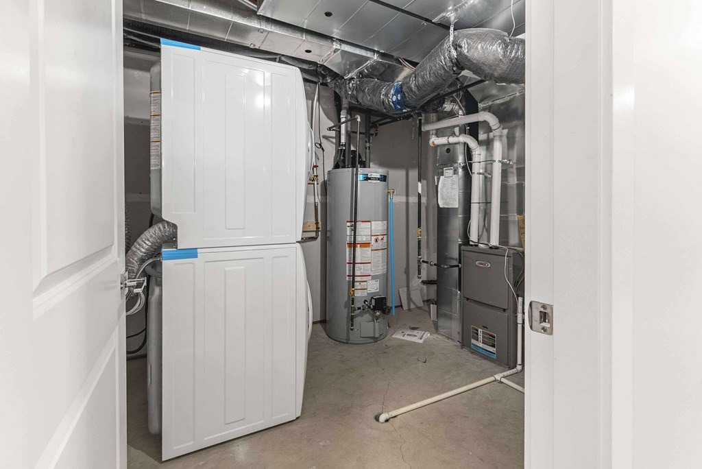 A white refrigerator is in a room with a lot of pipes.
