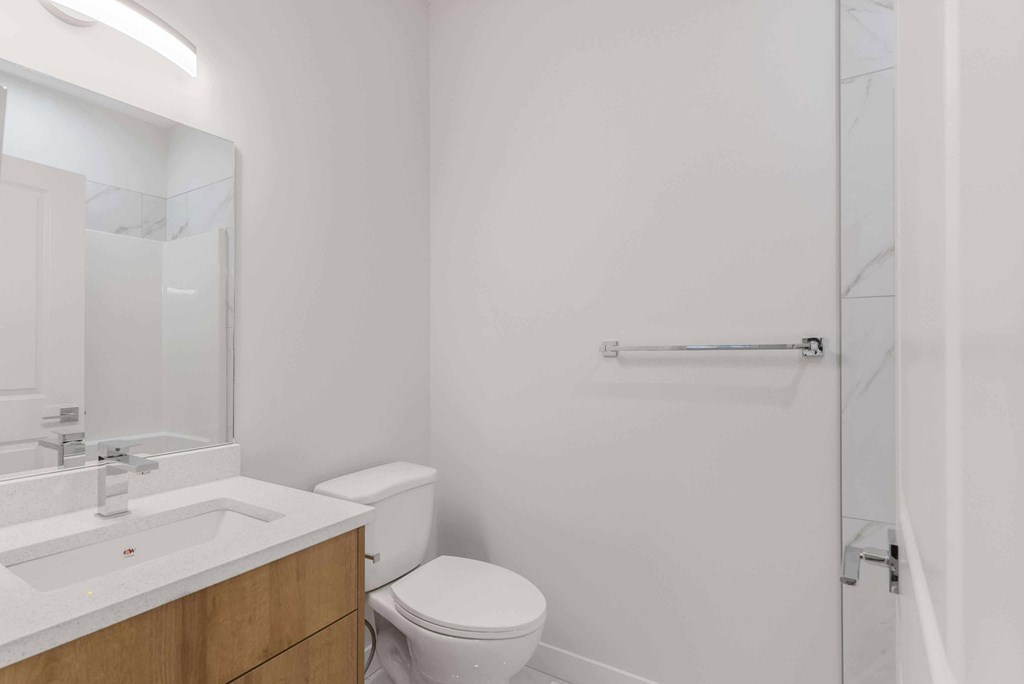 A white bathroom with a toilet, sink, and shower.
