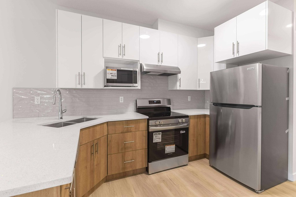 A modern kitchen with a stainless steel refrigerator, microwave, and oven.
