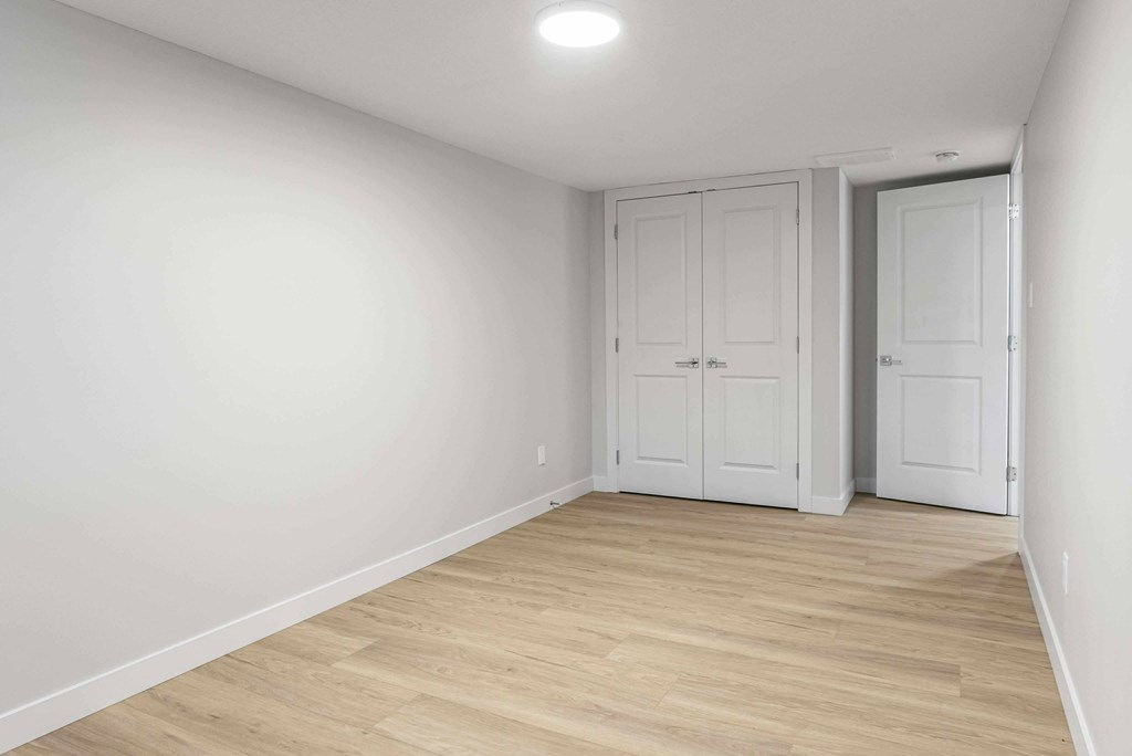 A room with two white doors and a light on the ceiling.