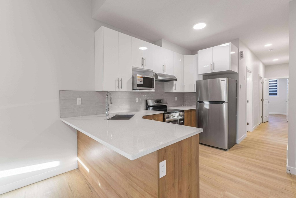 A modern kitchen with a white countertop and stainless steel appliances.