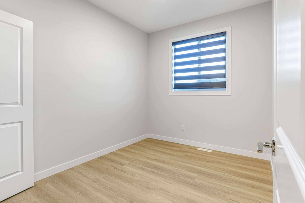 A room with a white door and a window with blinds.