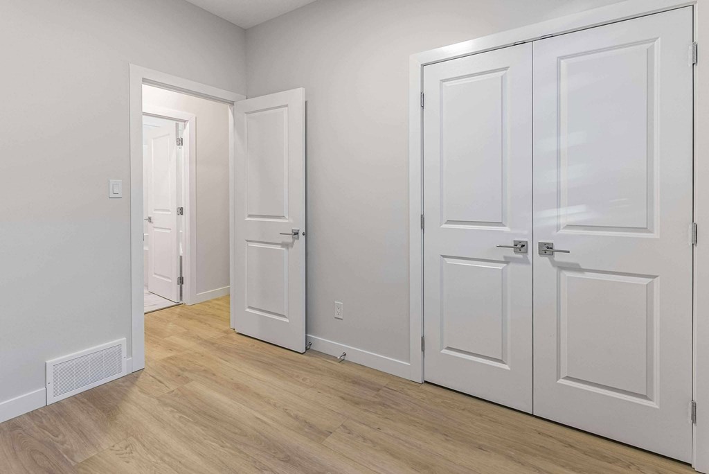 A room with three white doors and a wooden floor.