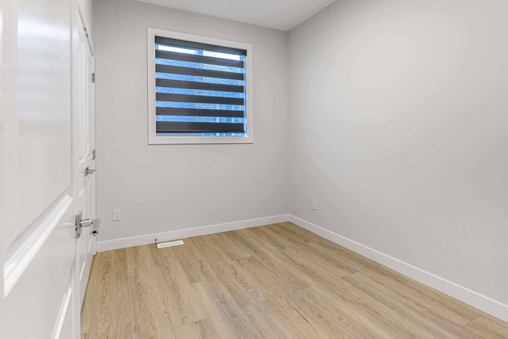 A room with a window and wooden flooring.