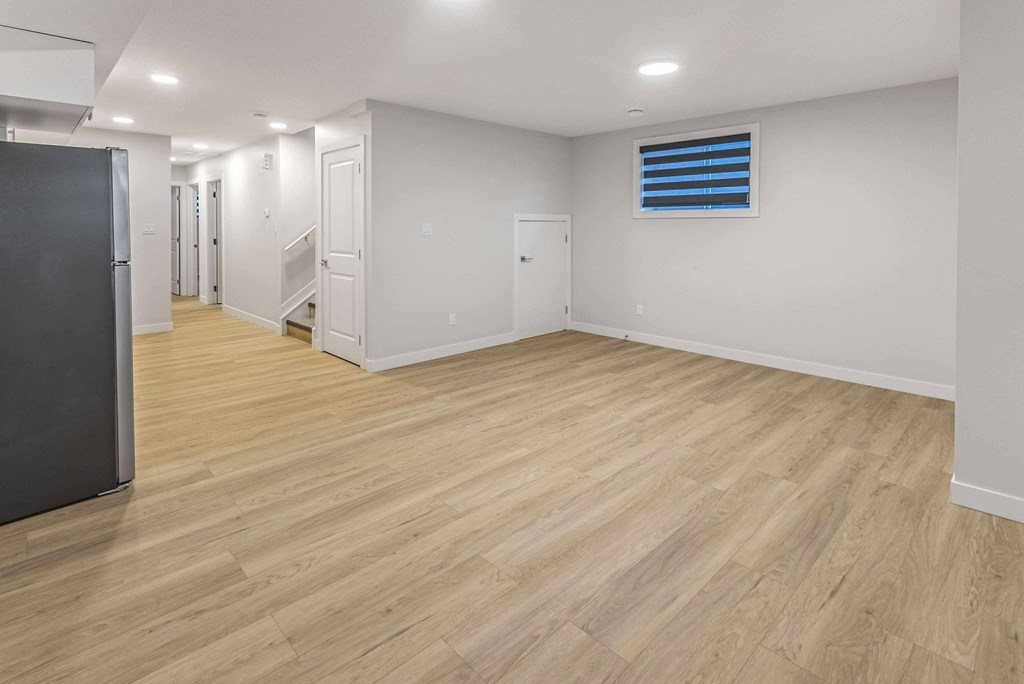 A spacious room with wooden flooring and white walls.