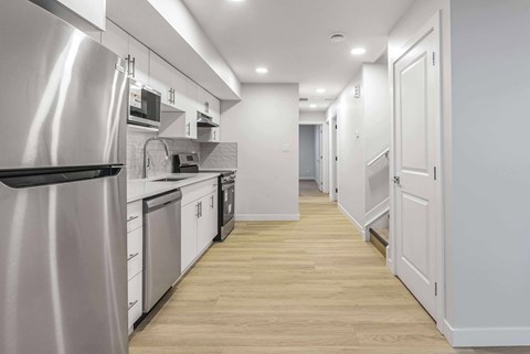 A modern kitchen with a stainless steel refrigerator and wooden flooring.