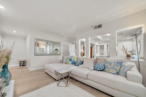 A white couch with blue and white pillows sits in a spacious living room.