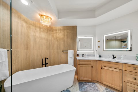A modern bathroom with a white bathtub and wooden walls.