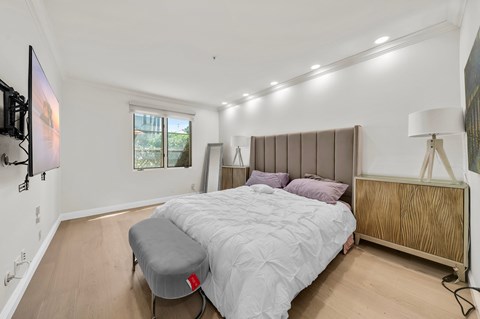 A bedroom with a bed, a bench, and a television.
