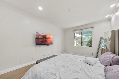 A bedroom with a large bed and a painting on the wall.
