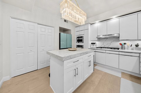 A kitchen with white cabinets and a marble countertop.