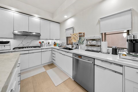 A modern kitchen with white cabinets and stainless steel appliances.