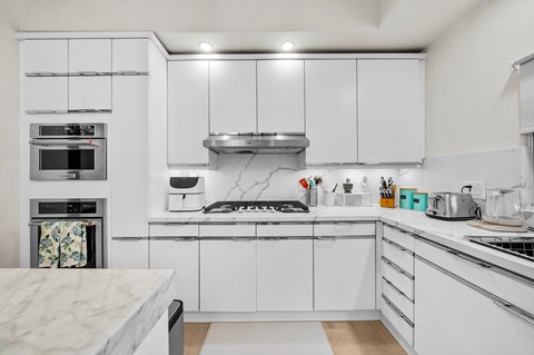 A modern kitchen with white cabinets and appliances.
