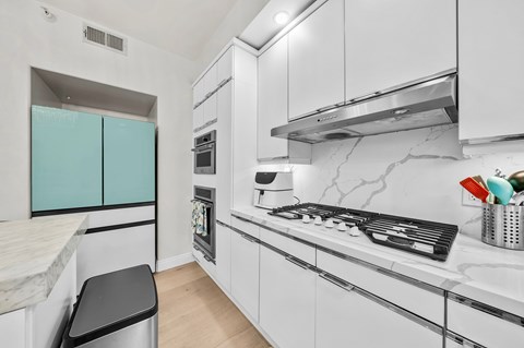 A modern kitchen with white cabinets and a marble backsplash.