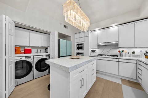 A modern kitchen with white cabinets and a marble island.