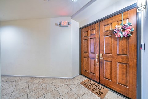 A wooden door with a floral arrangement on top and a sign that says "EXIT" on the wall above it.