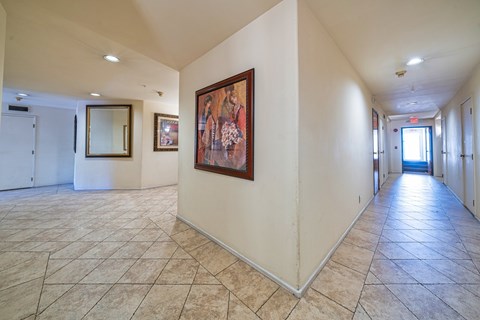 A hallway with a painting on the wall and tiled flooring.