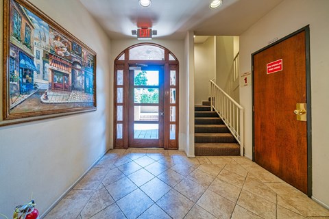 A hallway with a painting on the wall and a staircase.