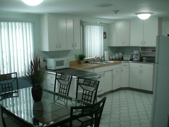 A kitchen with white cabinets and a glass table.