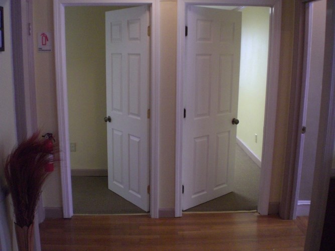 A hallway with two white doors and a red object on the left.