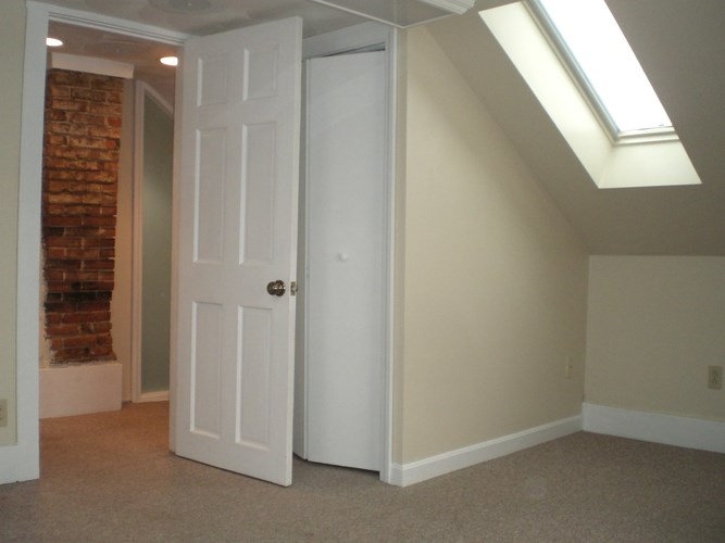 A white door is in a room with a skylight.